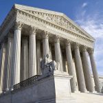 Supreme Court building with columns and statue in front.