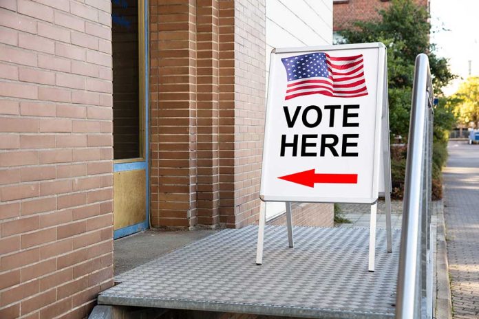 "Vote Here" sign with arrow and American flag.