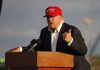 Person speaking at a podium wearing a red hat.