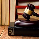 Gavel resting on books in front of bookshelf.