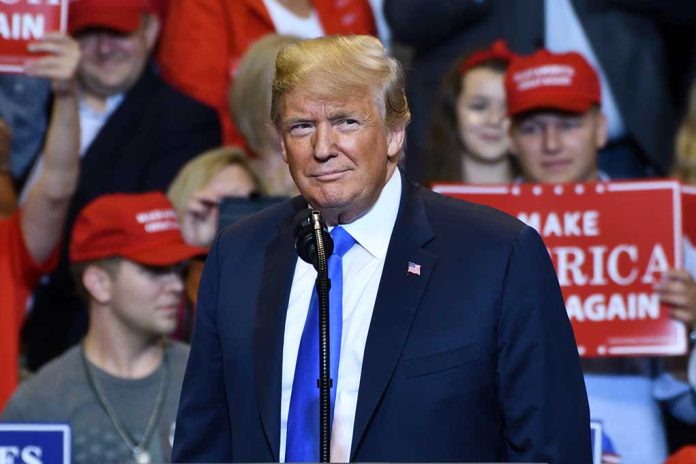 Person speaking at a rally with supporters behind.