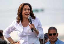 Woman speaking into microphone at outdoor event.