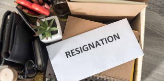 Envelope labeled "RESIGNATION" atop office supplies in box.