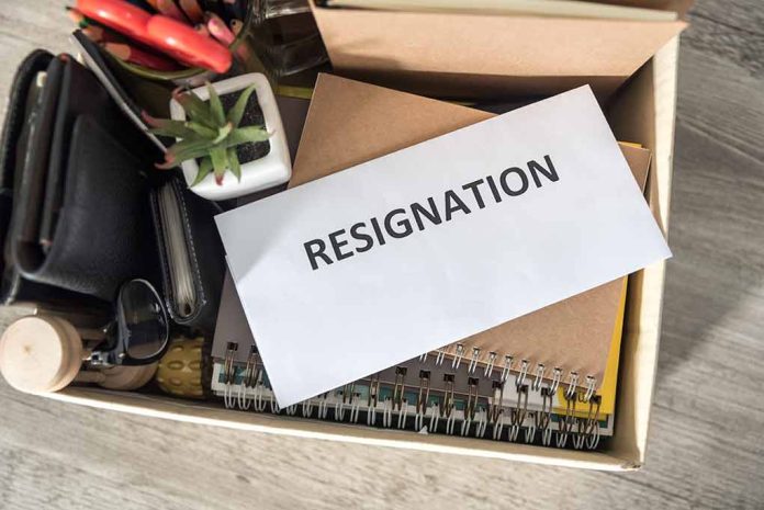 Envelope labeled "RESIGNATION" atop office supplies in box.