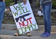 Protest sign reads: "We Will Not Comply".