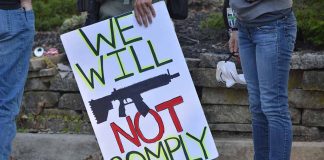 Protest sign reads: "We Will Not Comply".