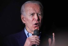 Man speaking into a microphone, black background.