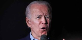 Man speaking into a microphone, black background.