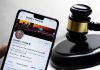 Smartphone displaying Twitter profile beside a judge’s gavel.