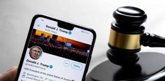 Smartphone displaying Twitter profile beside a judge’s gavel.