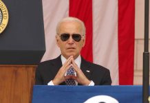 Man in sunglasses in front of American flag.