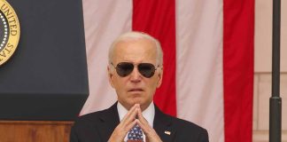 Man in sunglasses in front of American flag.