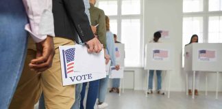 People standing in line holding voting papers.