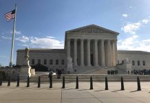 U.S. Supreme Court Building with flag and people outside.