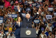 Man and woman celebrating on stage with supporters.