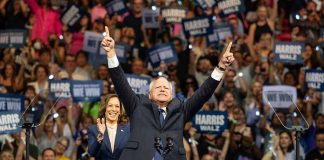 Man and woman celebrating on stage with supporters.