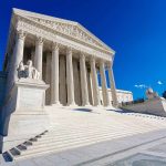 Supreme Court building with steps and statues.