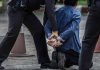 Police officers arresting and handcuffing a man kneeling.