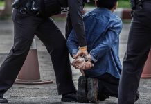 Police officers arresting and handcuffing a man kneeling.