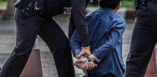 Police officers arresting and handcuffing a man kneeling.