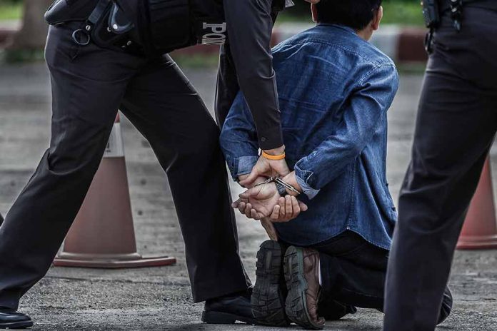 Police officers arresting and handcuffing a man kneeling.