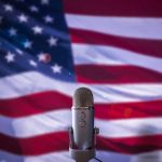 Microphone in front of blurred American flag.