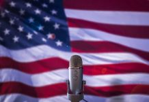 Microphone in front of blurred American flag.