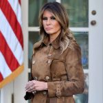 Woman in brown coat with American flag background.