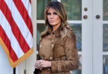 Woman in brown coat with American flag background.