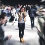 Person covering face while surrounded by blurred crowd