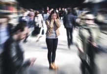 Person covering face while surrounded by blurred crowd