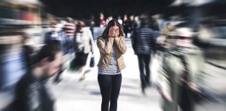 Person covering face while surrounded by blurred crowd