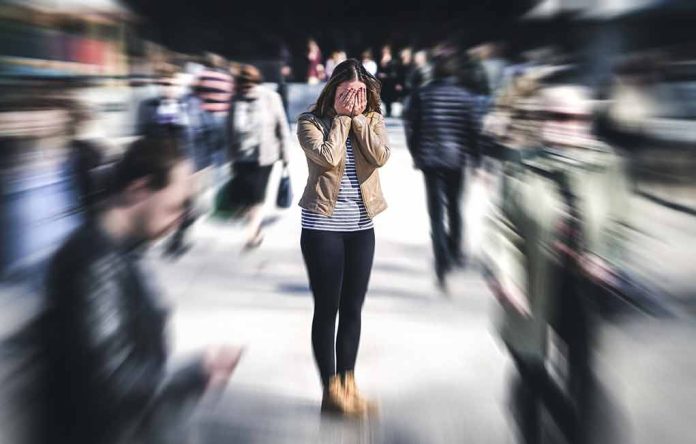 Person covering face while surrounded by blurred crowd