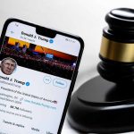 Smartphone displaying Twitter profile beside a judge’s gavel.