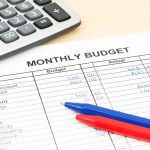 Calculator and pens on monthly budget sheet