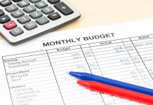 Calculator and pens on monthly budget sheet