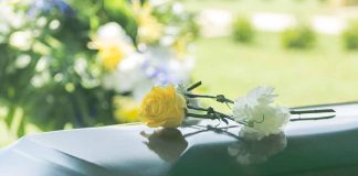 Two flowers on a casket at a funeral.