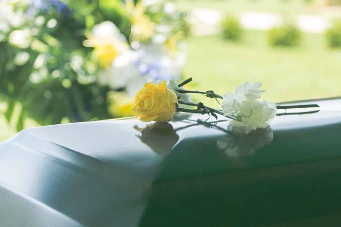 Two flowers on a casket at a funeral.