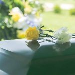 Two flowers on a casket at a funeral.