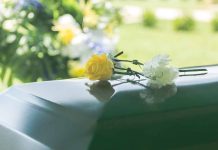 Two flowers on a casket at a funeral.