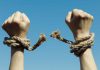 Hands with broken rope against blue sky