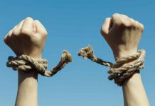 Hands with broken rope against blue sky