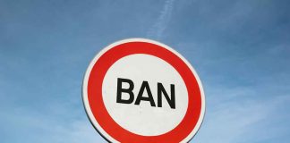 Traffic sign with the word BAN against sky