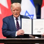 Man holding signed document with three visible flags