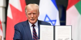 Man holding signed document with three visible flags