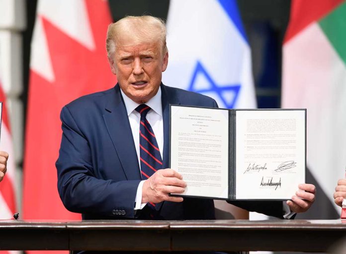 Man holding signed document with three visible flags