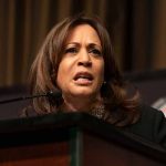 Woman speaking at podium with intense expression.