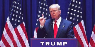 Person speaking at podium with multiple American flags.