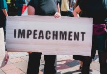 Person holding an "Impeachment" sign at protest.