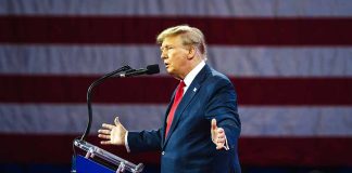 Person speaking at a podium with flag background.